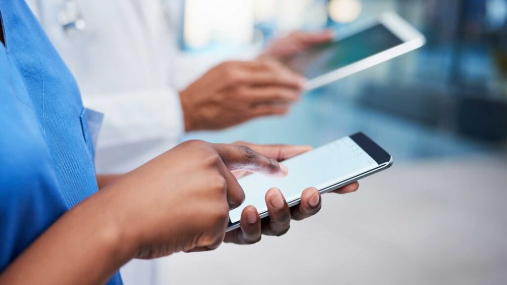 Shot of a medical practitioner using a cellphone with her colleague in the background, m360 research